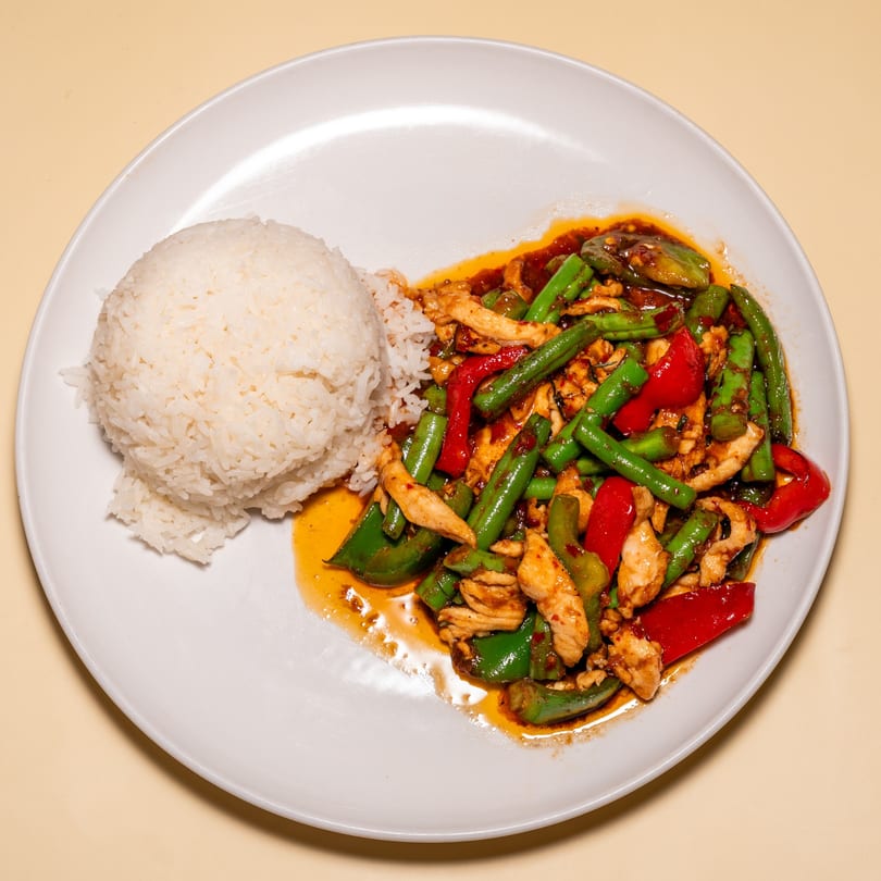 Racha Café's Thai dish with chicken, green beans, and red peppers, served with white rice.