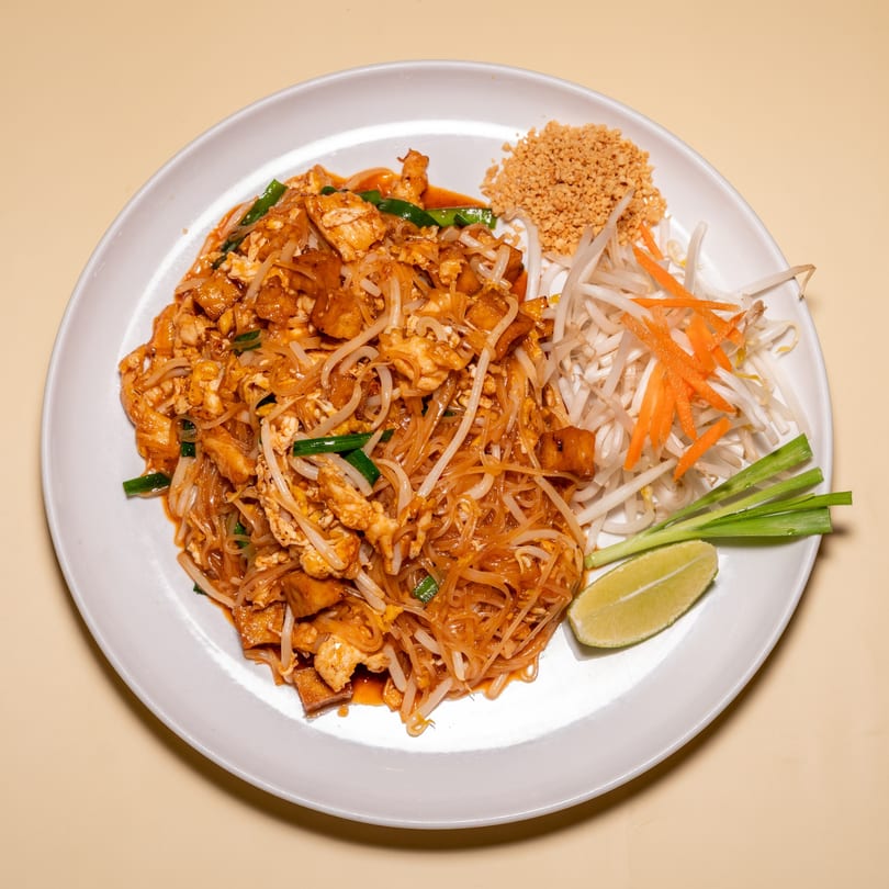 Racha Café's Pad Thai with noodles, chicken, tofu, bean sprouts, carrots, lime, and peanuts.